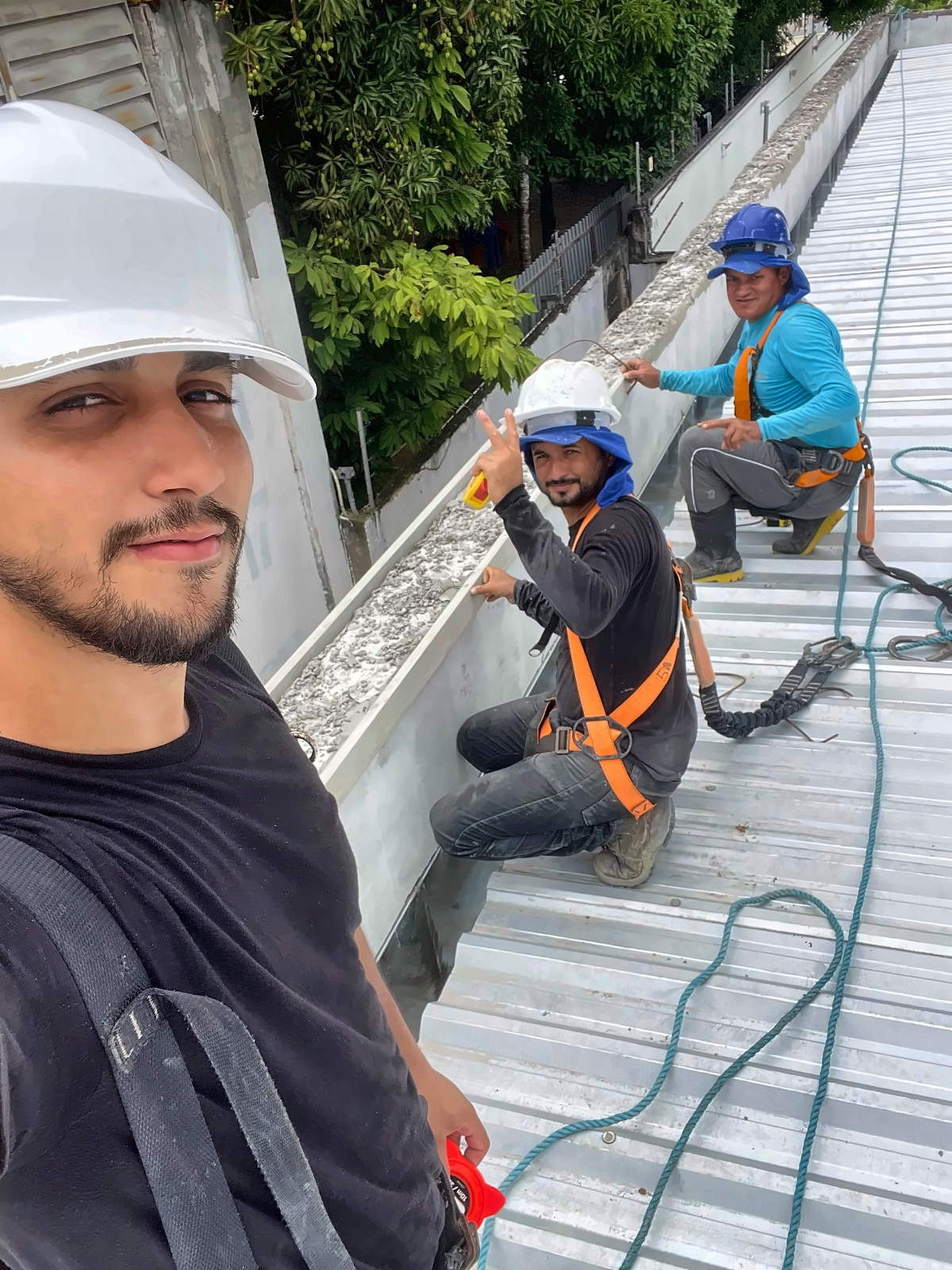 Equipe da Enobras trabalhando sobre cobertura metálica, com capacete e cinto de segurança