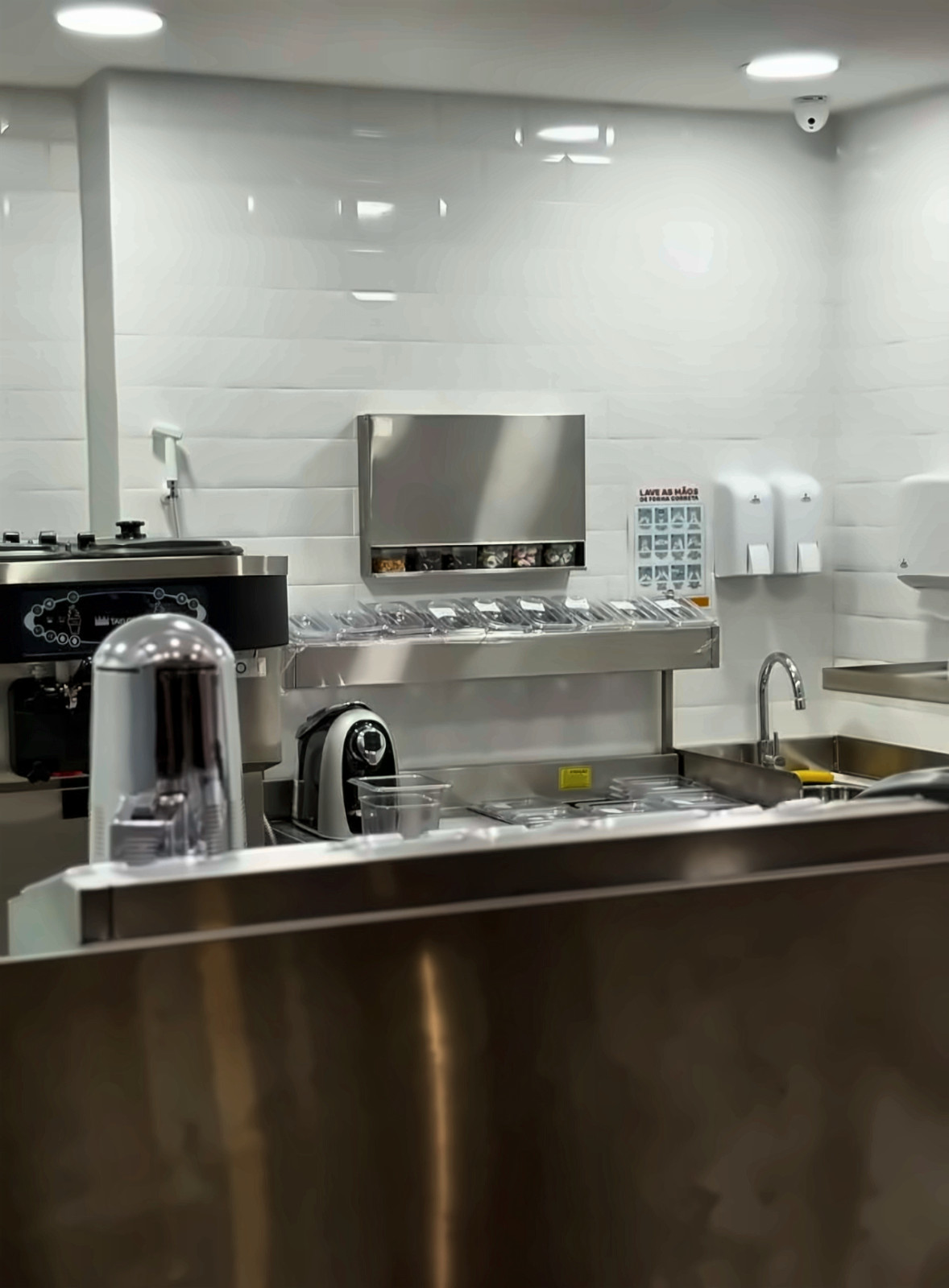 Área de preparo da loja Chiquinho Sorvetes, com bancada em inox e parede de azulejo