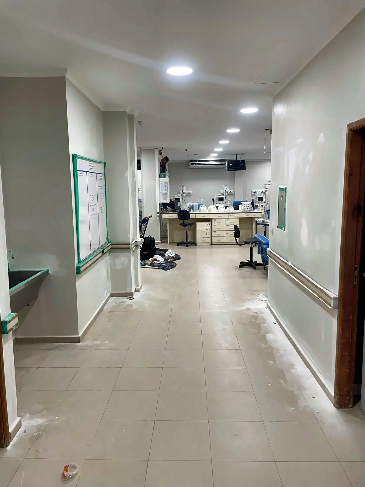 Corredor com paredes em preparação para pintura e acabamentos protegidos com fita